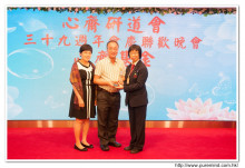 鍾孝新法師致送紀念品給去年競投聖品之熱心人士。